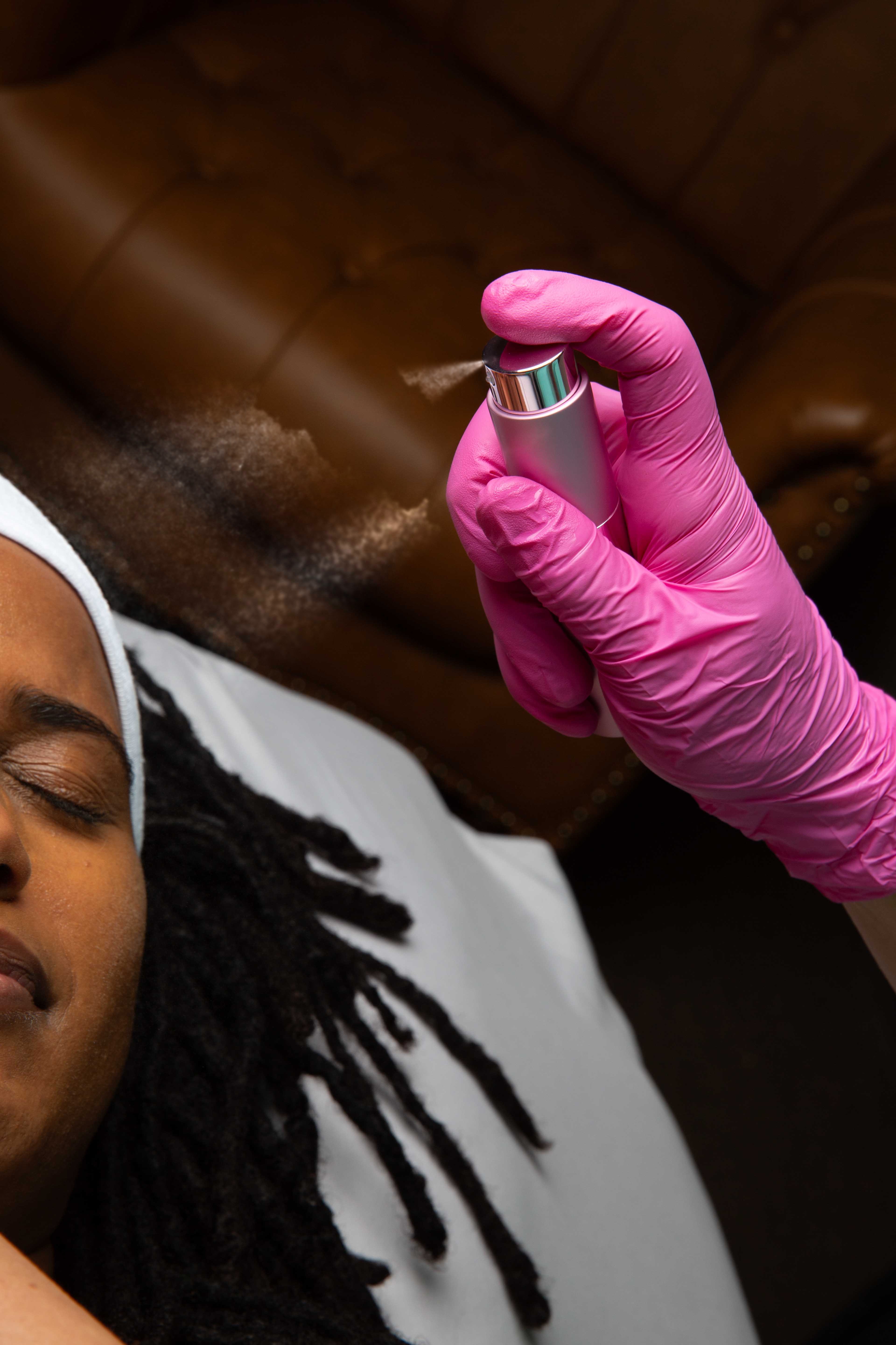 Practitioner misting clinical serum over a client’s face during clinical skincare