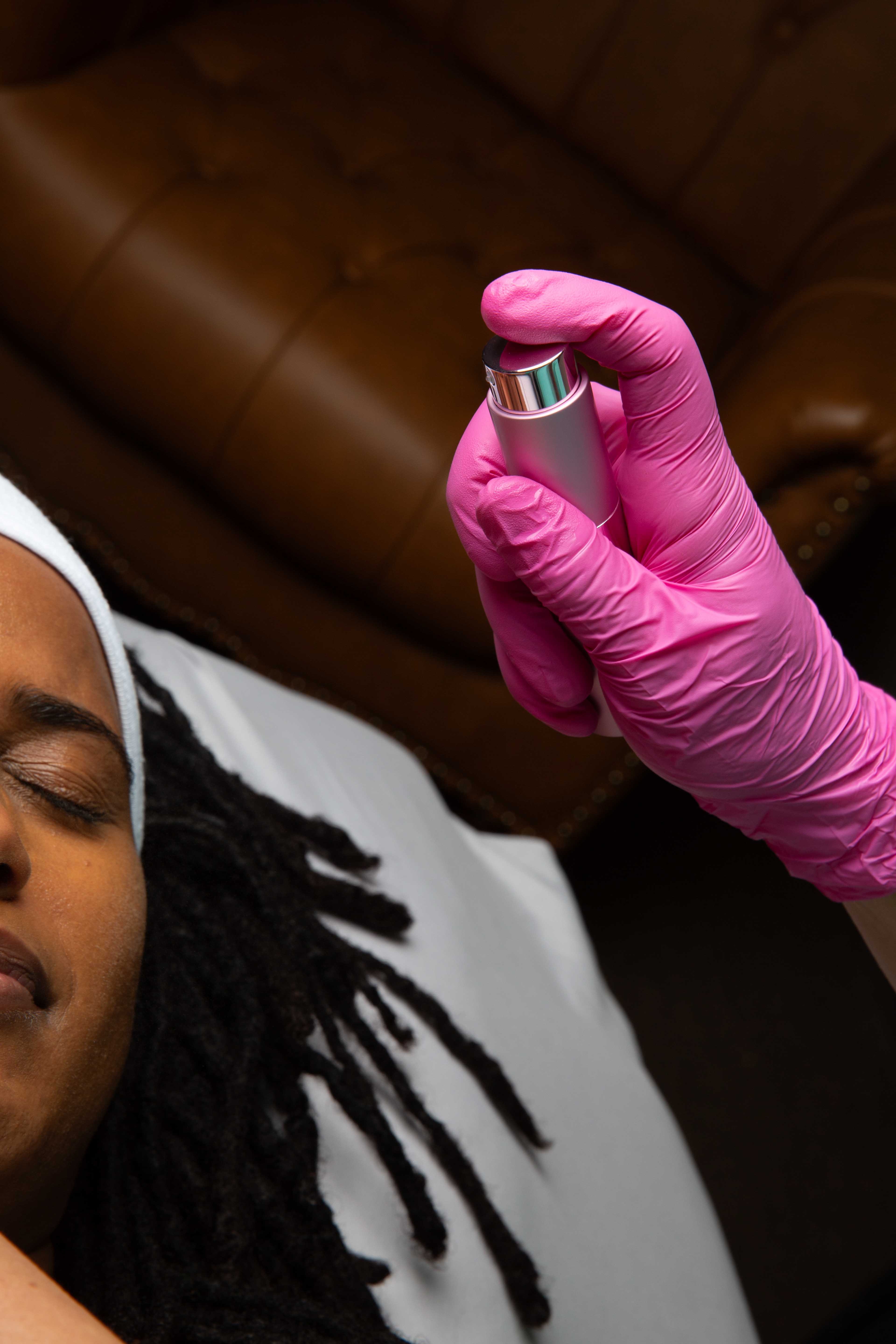 Practitioner misting regenerative serum over a client’s face during clinical skincare